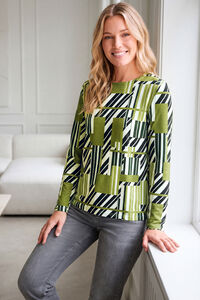 "L&auml;chelnde blonde Frau mit einem gr&uuml;n-schwarz-wei&szlig; gemusterten Langarmshirt"