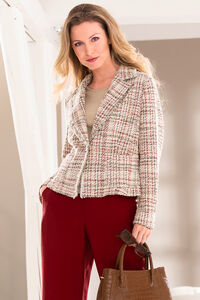 "Blonde Frau mit roter Hose und beige, leicht rotkarierten Blazer und Handtasche in der Hand."